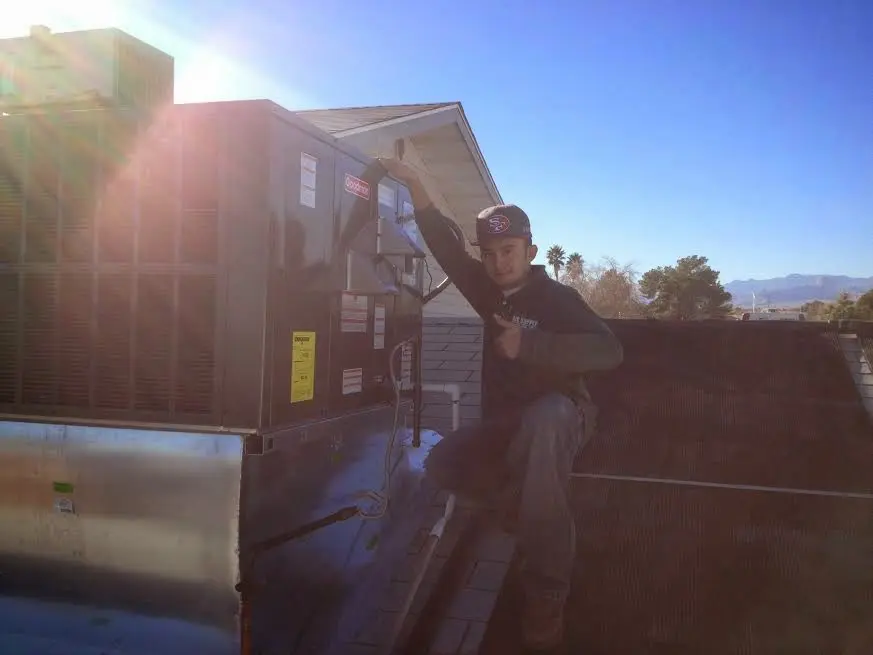 HVAC technician performing Air Duct Repair on a rooftop unit in Farmington